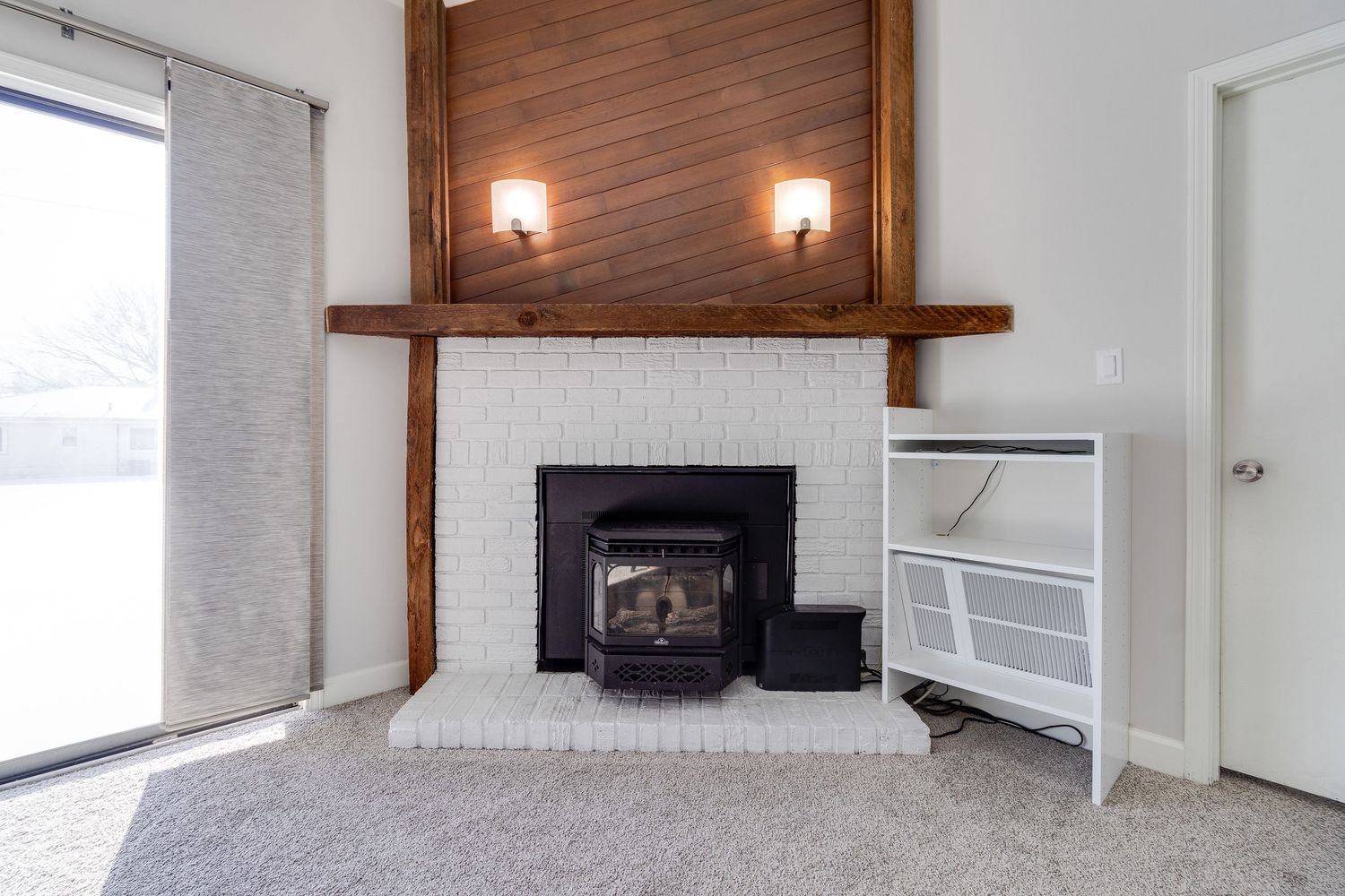 Rustic fireplace with white brick surround, wooden mantel, and built-in shelving.