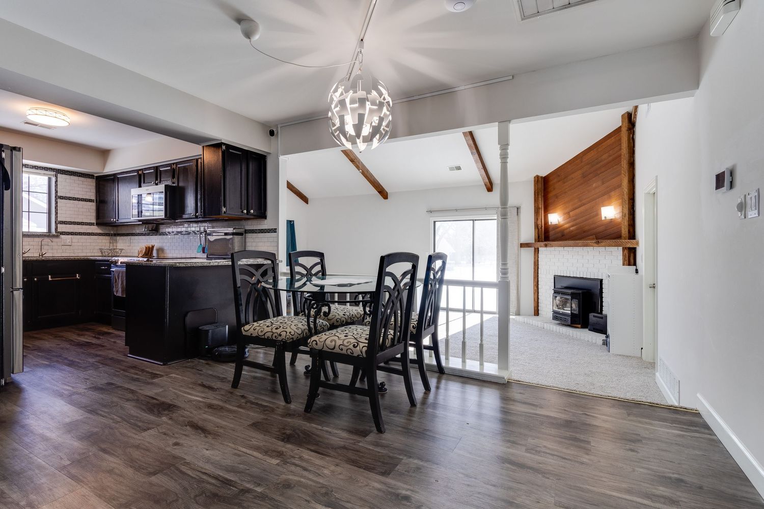 Contemporary open-concept dining area with dark wood floors and modern lighting fixture.