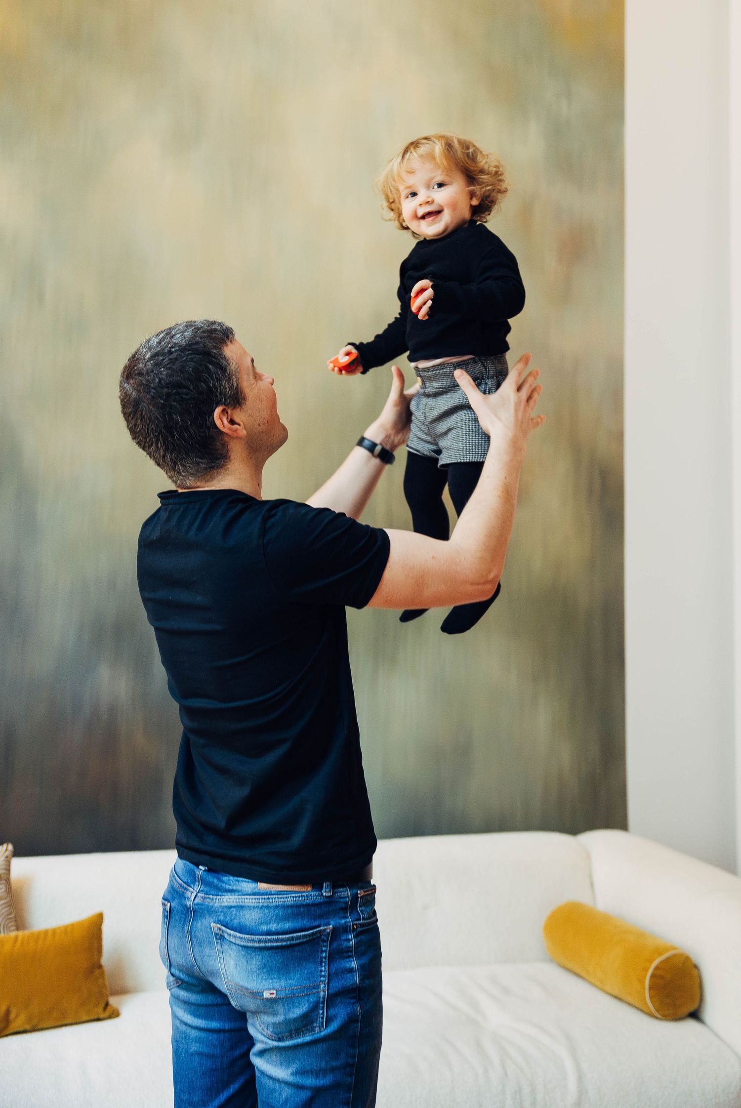 A sequence of playful moments captured on a bed showing joyful interaction between an adult and small child in casual attire.