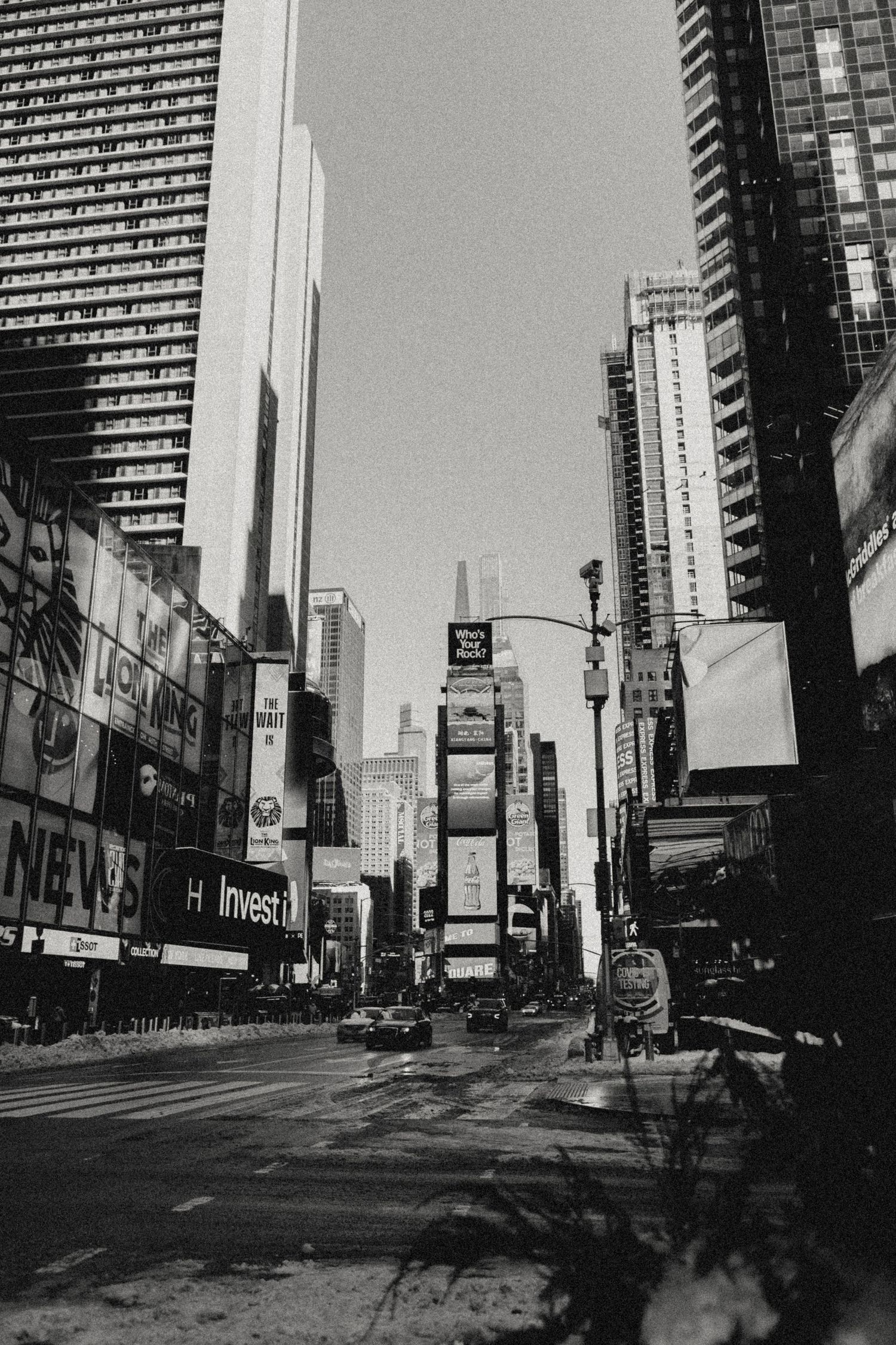 Black and white urban photograph of Times Square in New York City with tall buildings and billboards.