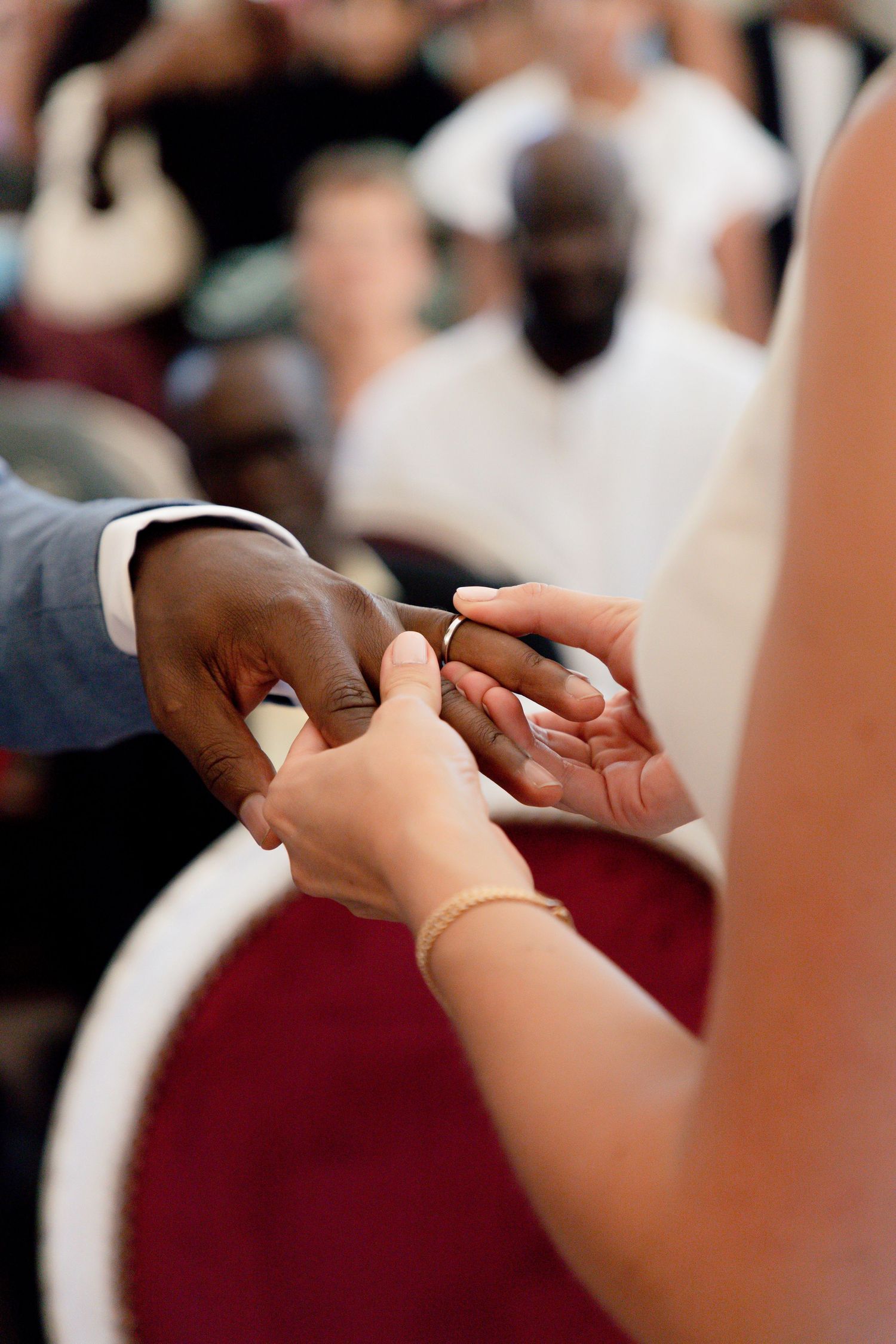 Close-up shot of wedding ring exchange ceremony with hands touching.