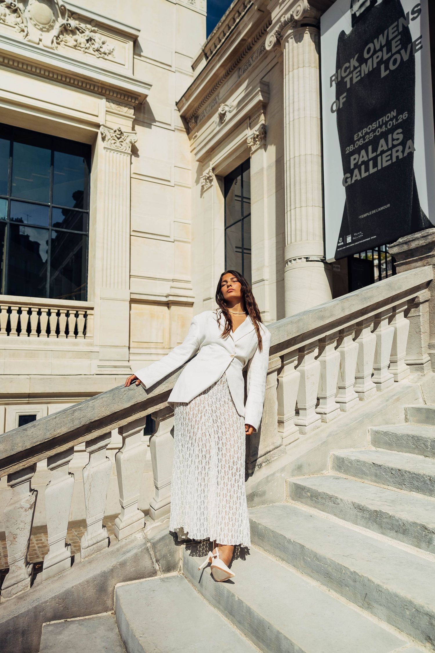 Fashion photography featuring white tailored outfit against classical building facade.