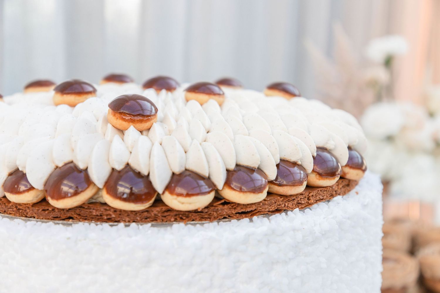 Row of delicate whipped cream decorations on a chocolate dessert.