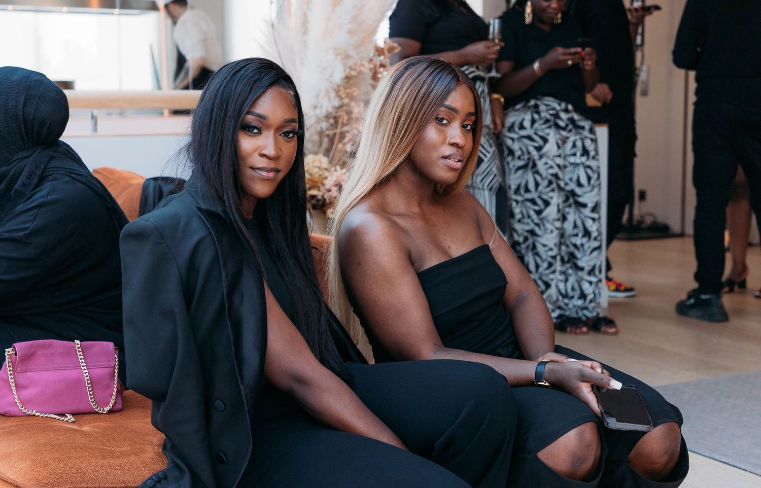 Friends relaxing on indoor steps in casual black outfits.