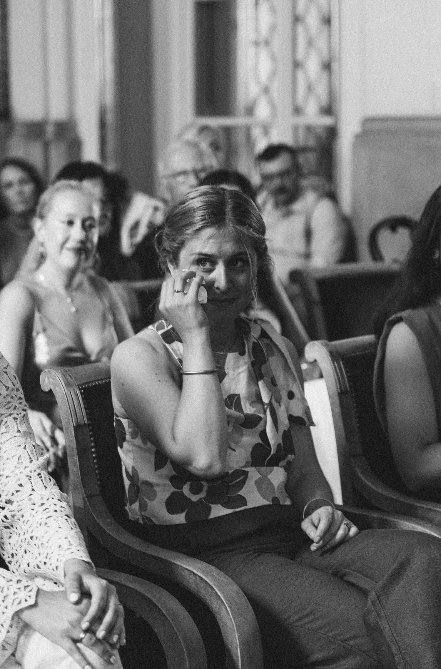 A candid black and white photo of guests showing emotion during an indoor event.