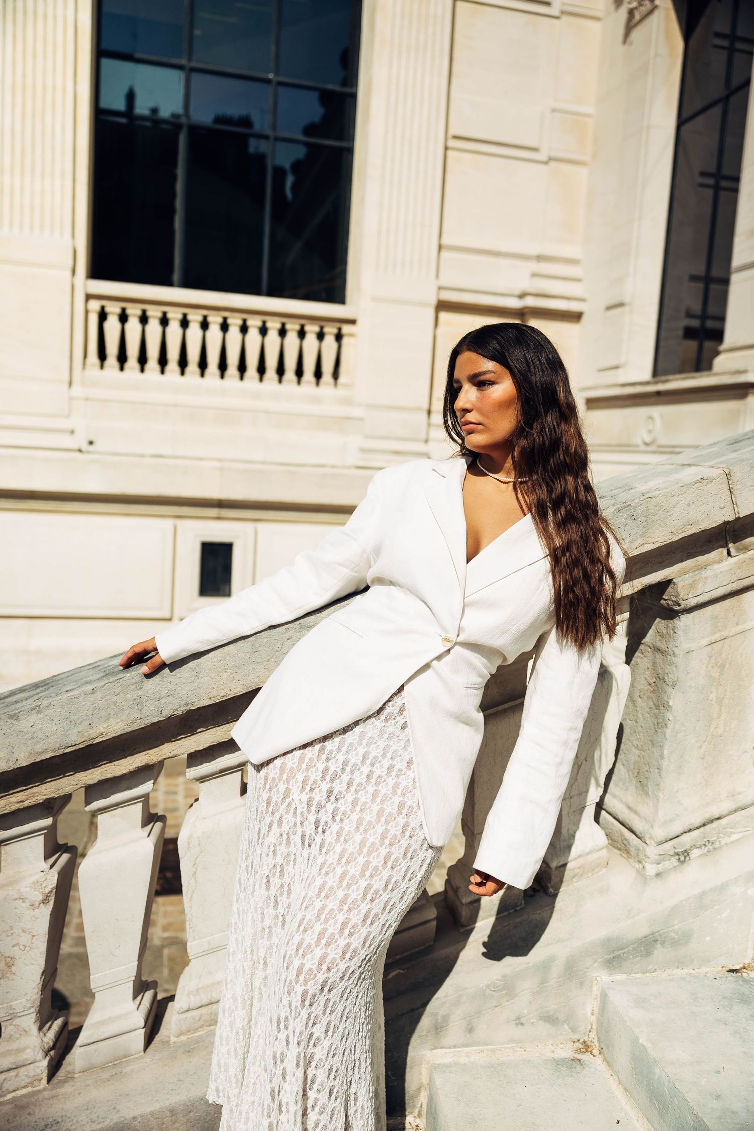 Fashion photoshoot featuring a white blazer and lace dress ensemble on classical architectural steps.