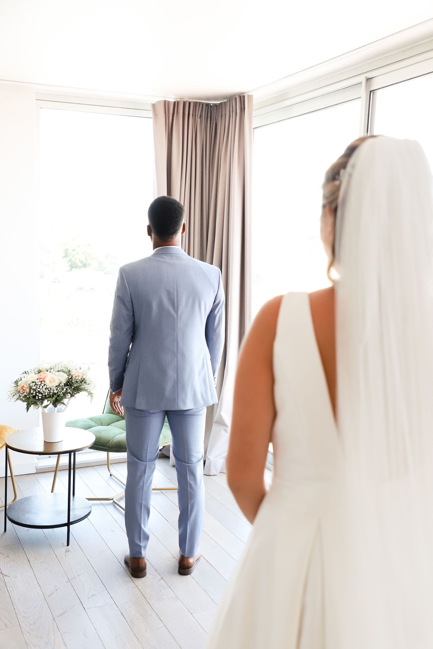 Wedding photos showing a couple in formal attire in a bright modern room with large windows.
