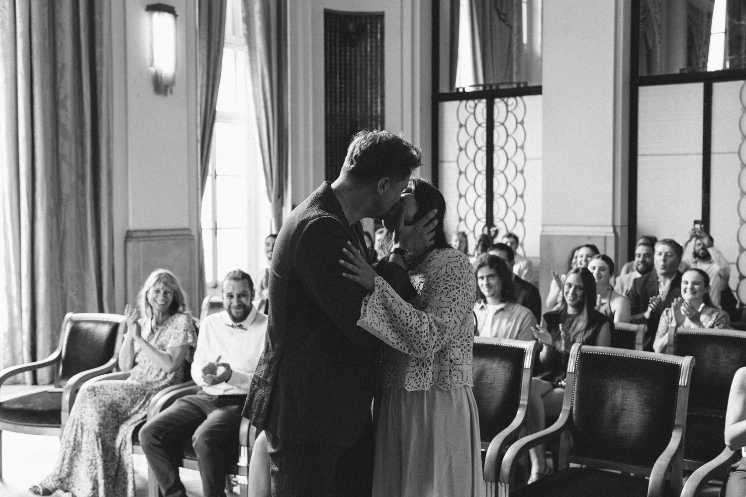 Black and white photo of guests gathered in elegant room with vintage furniture and decor.
