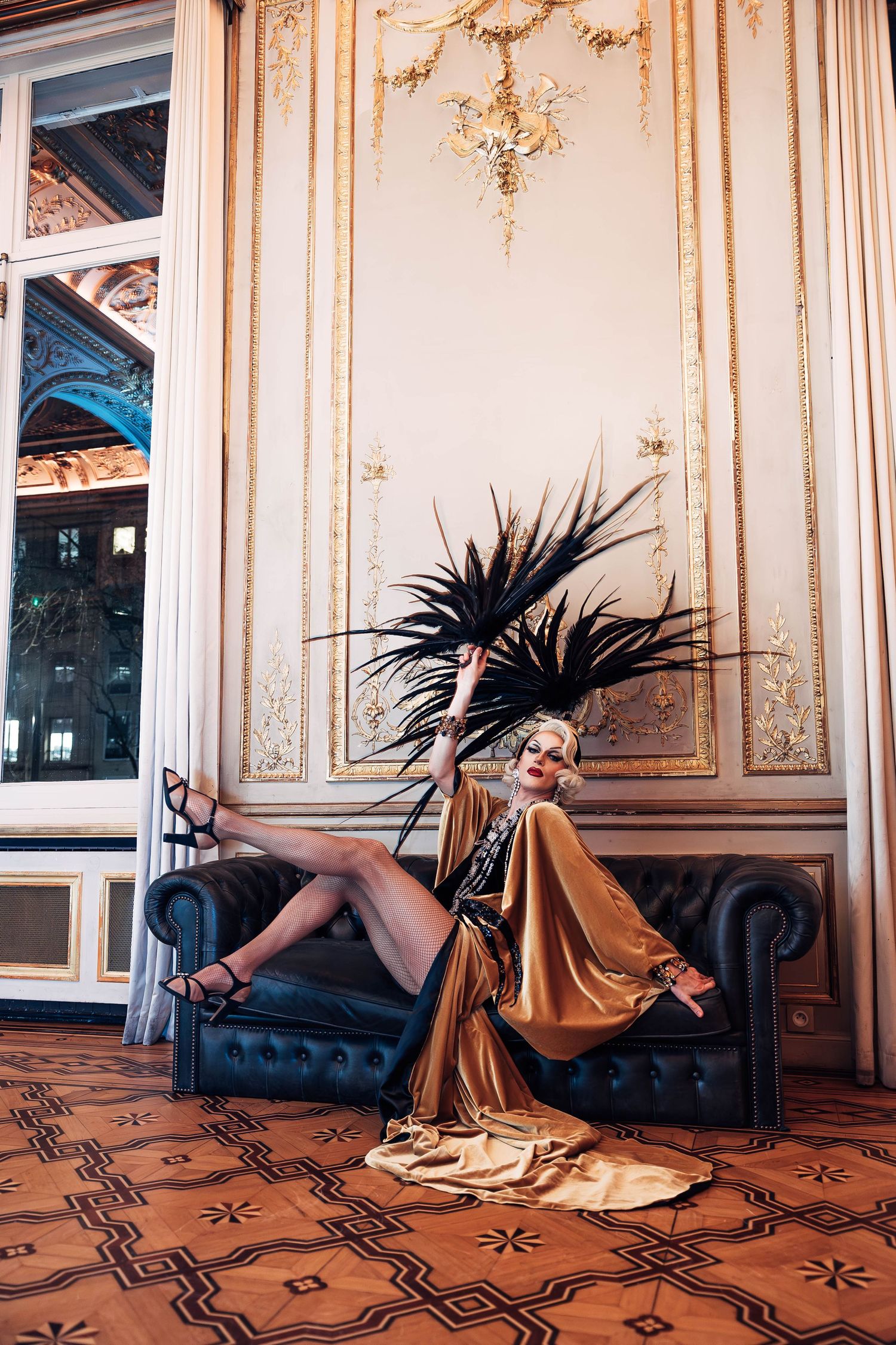 Glamorous 1920s inspired photoshoot featuring gold decor and dramatic black feather arrangement.