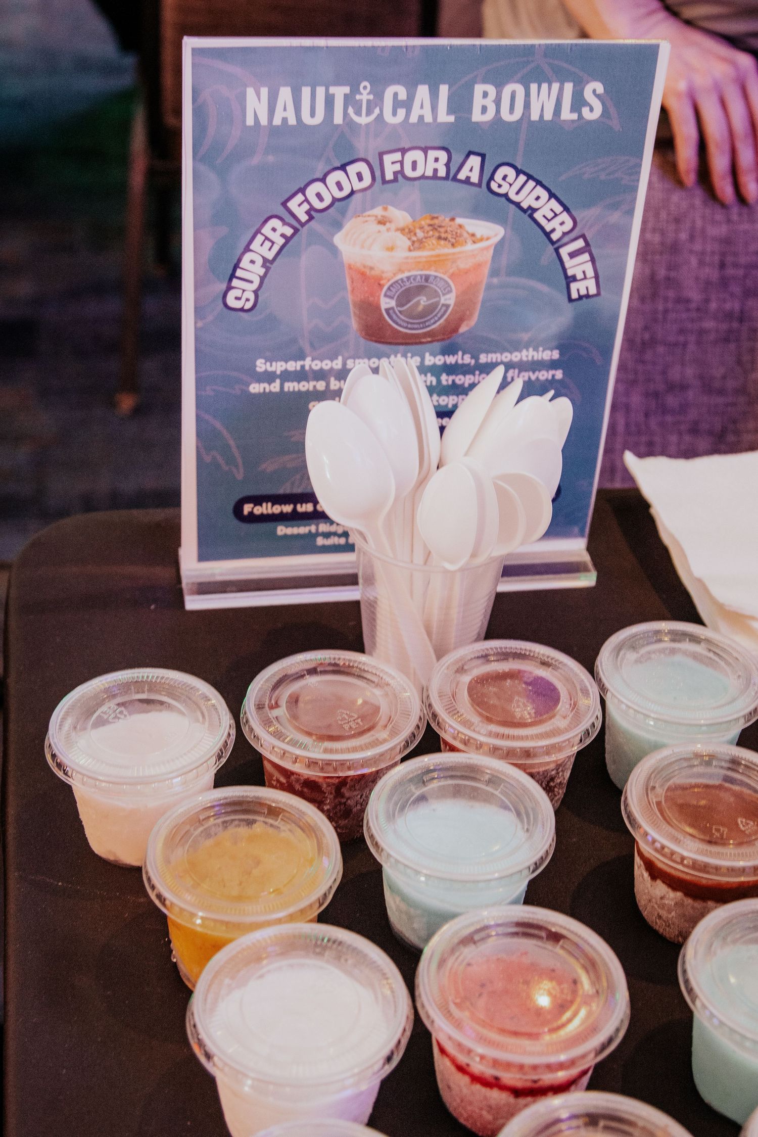 Row of colorful smoothie bowls with nautical theme signage displayed at a food counter.