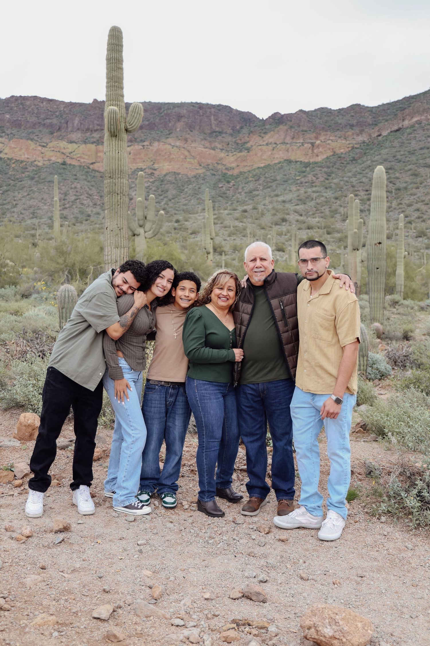 Family group photo among tall saguaro cacti in Arizona desert landscape.
