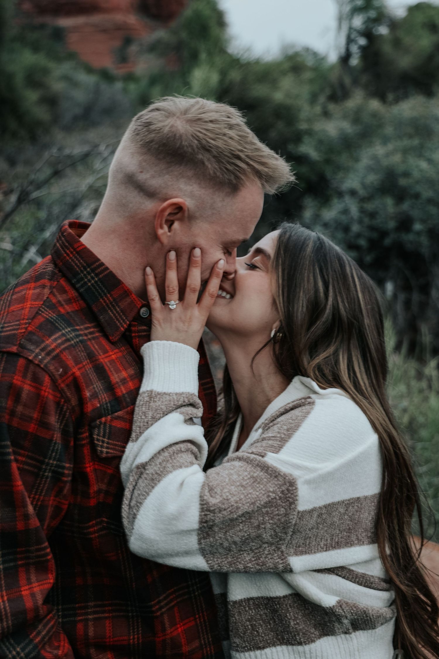 Couple in cozy sweaters sharing an intimate moment against a natural backdrop.