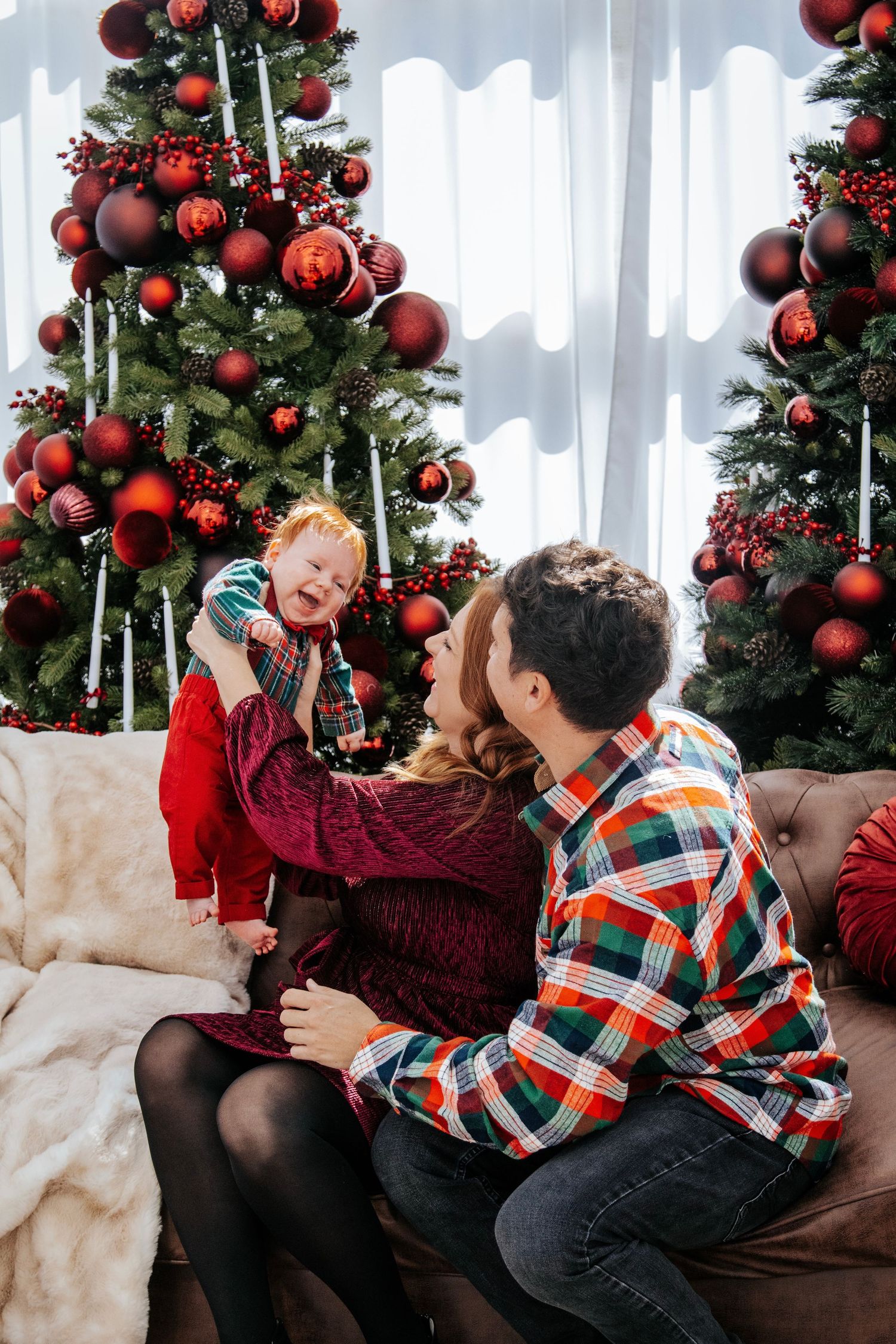 Cozy Christmas scene with plaid shirt and burgundy sweater in front of decorated tree.