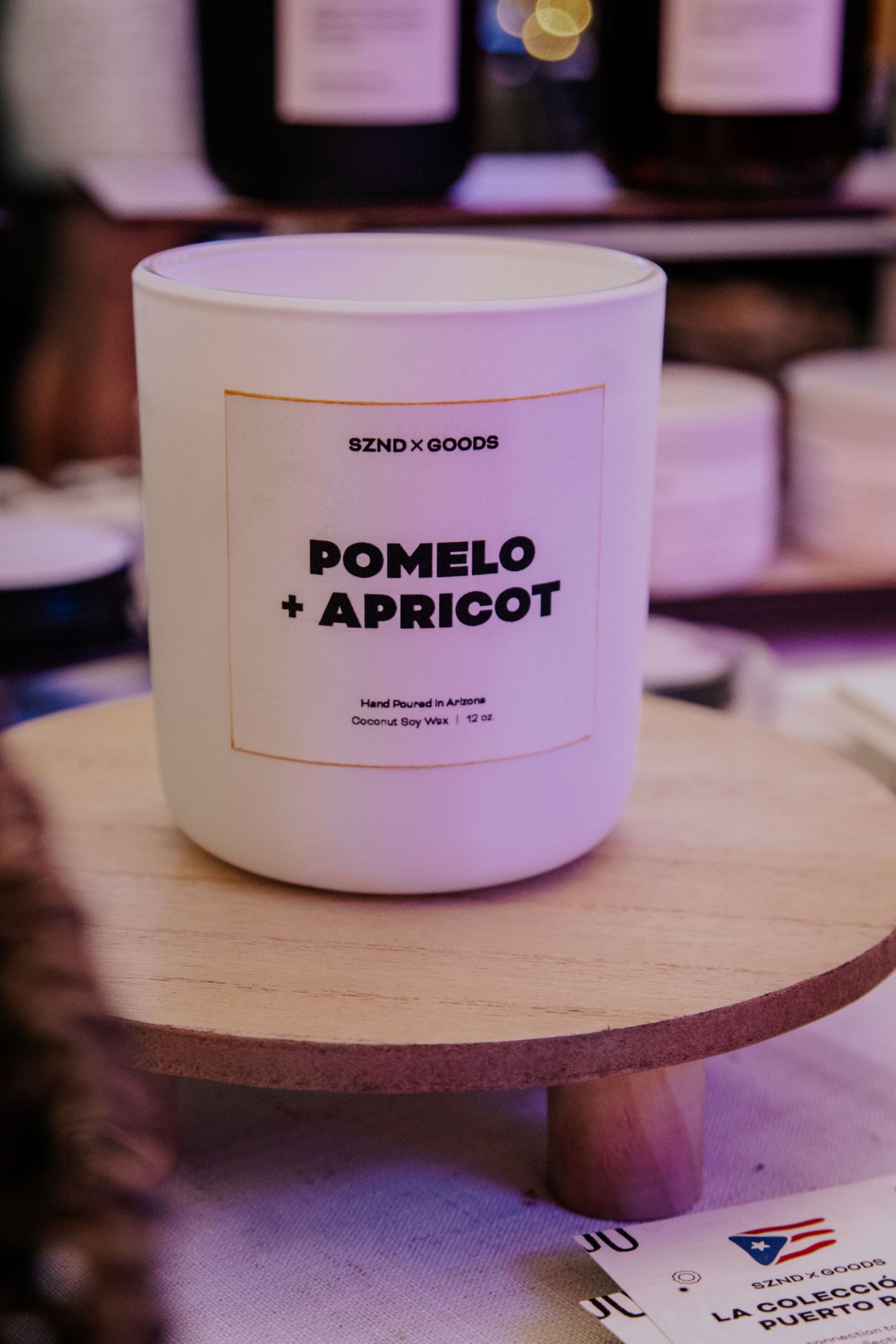 White ceramic bowls labeled Pomelo and Apricot displayed on wooden pedestals.
