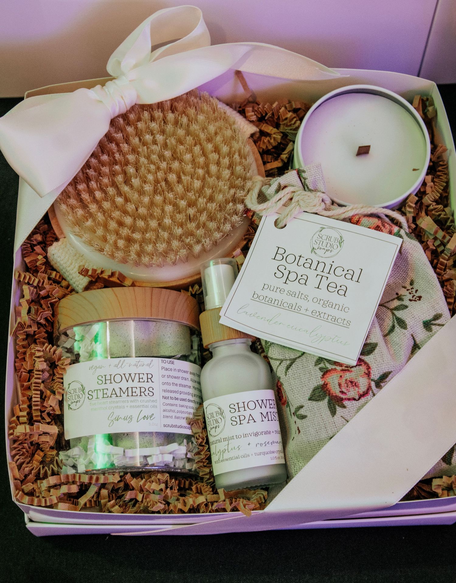 Spa and wellness gift set featuring botanical products, candles, and bath accessories arranged in a display.
