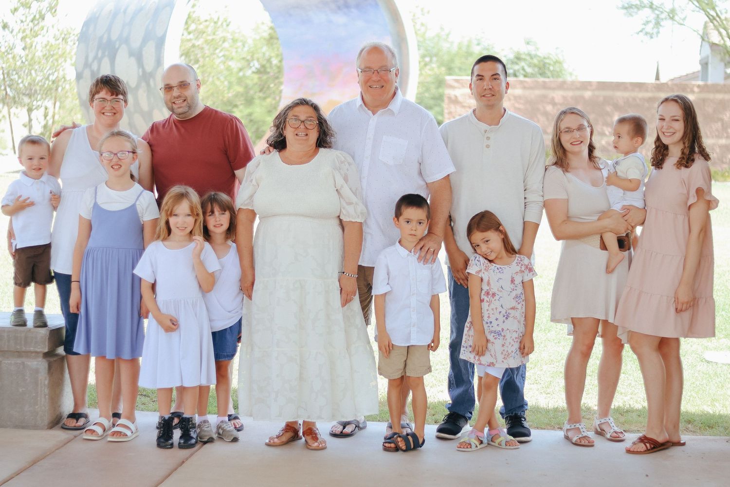 Series of casual outdoor family portraits with coordinated light-colored outfits.