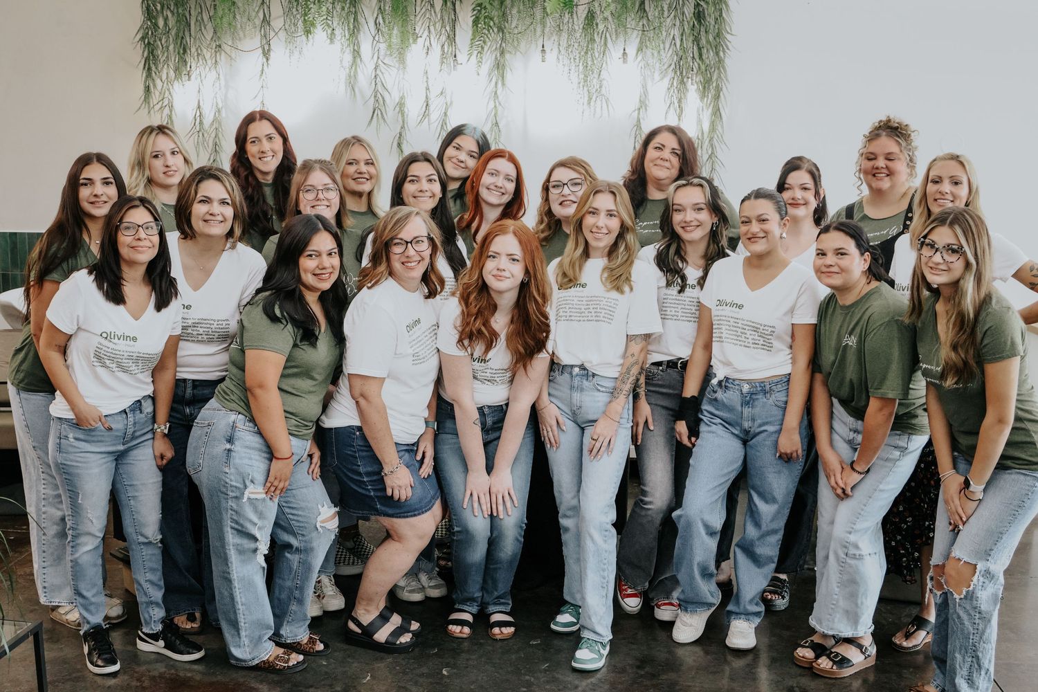 Large group of people wearing white shirts and jeans posing together for a casual outdoor photo shoot.