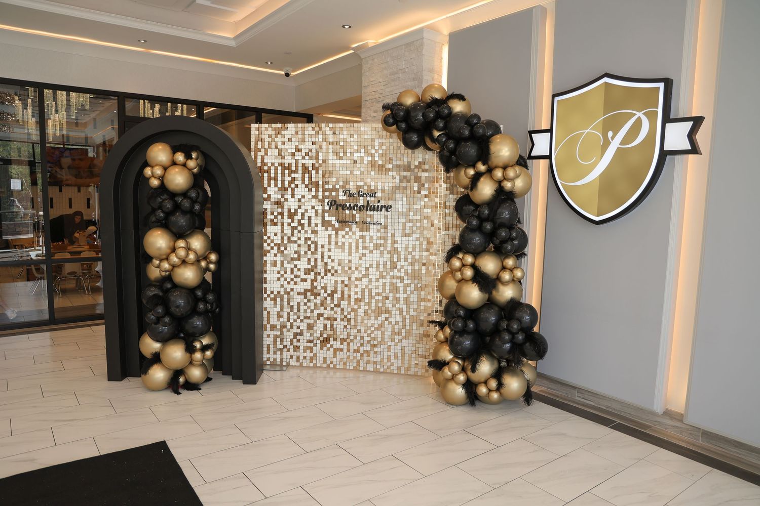 Elegant retail store entrance with gold and black balloon arch decorations and illuminated white signage.