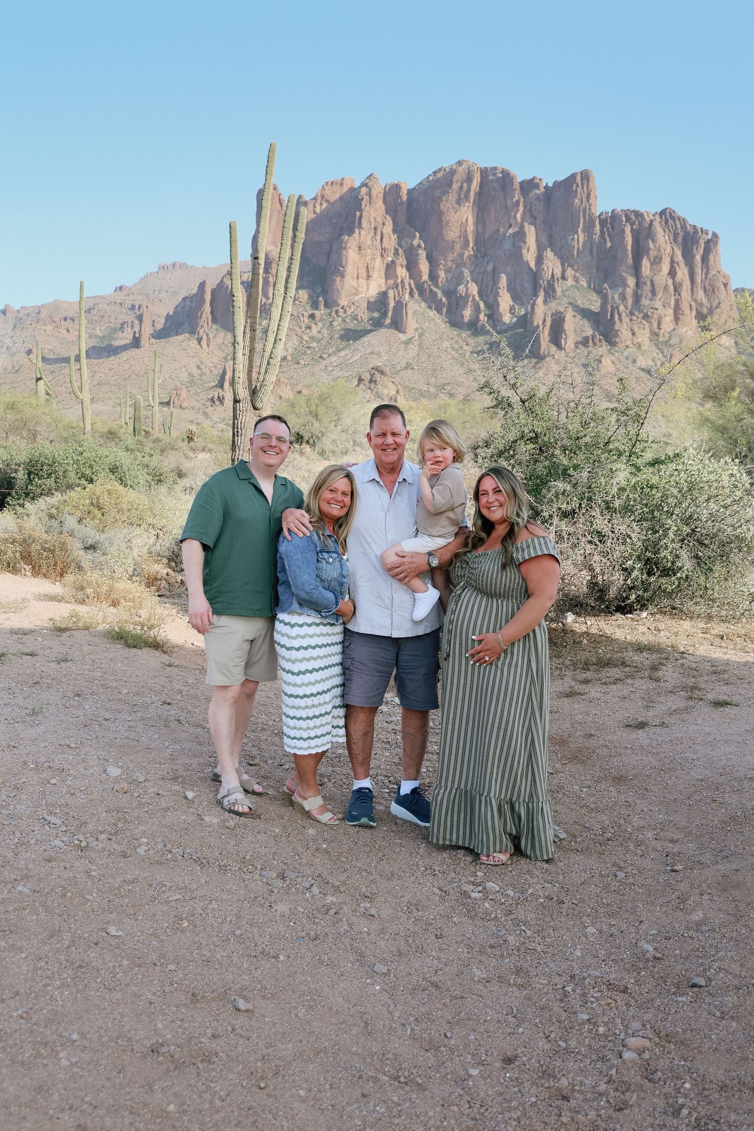 Family of five posing together in Arizona desert with Superstition Mountains and saguaro cactus in background.