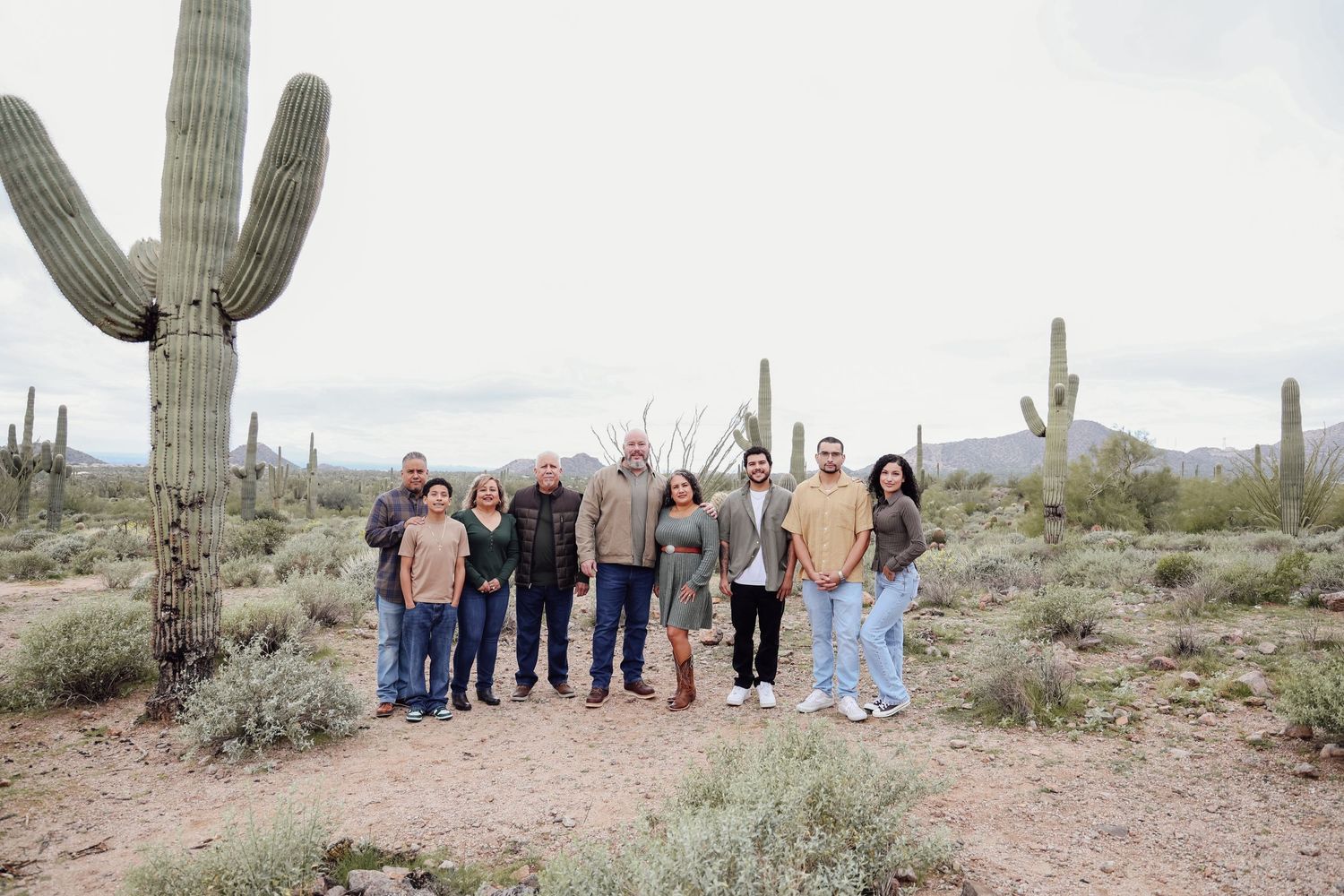 Group portrait with saguaro cacti and desert mountains in background.