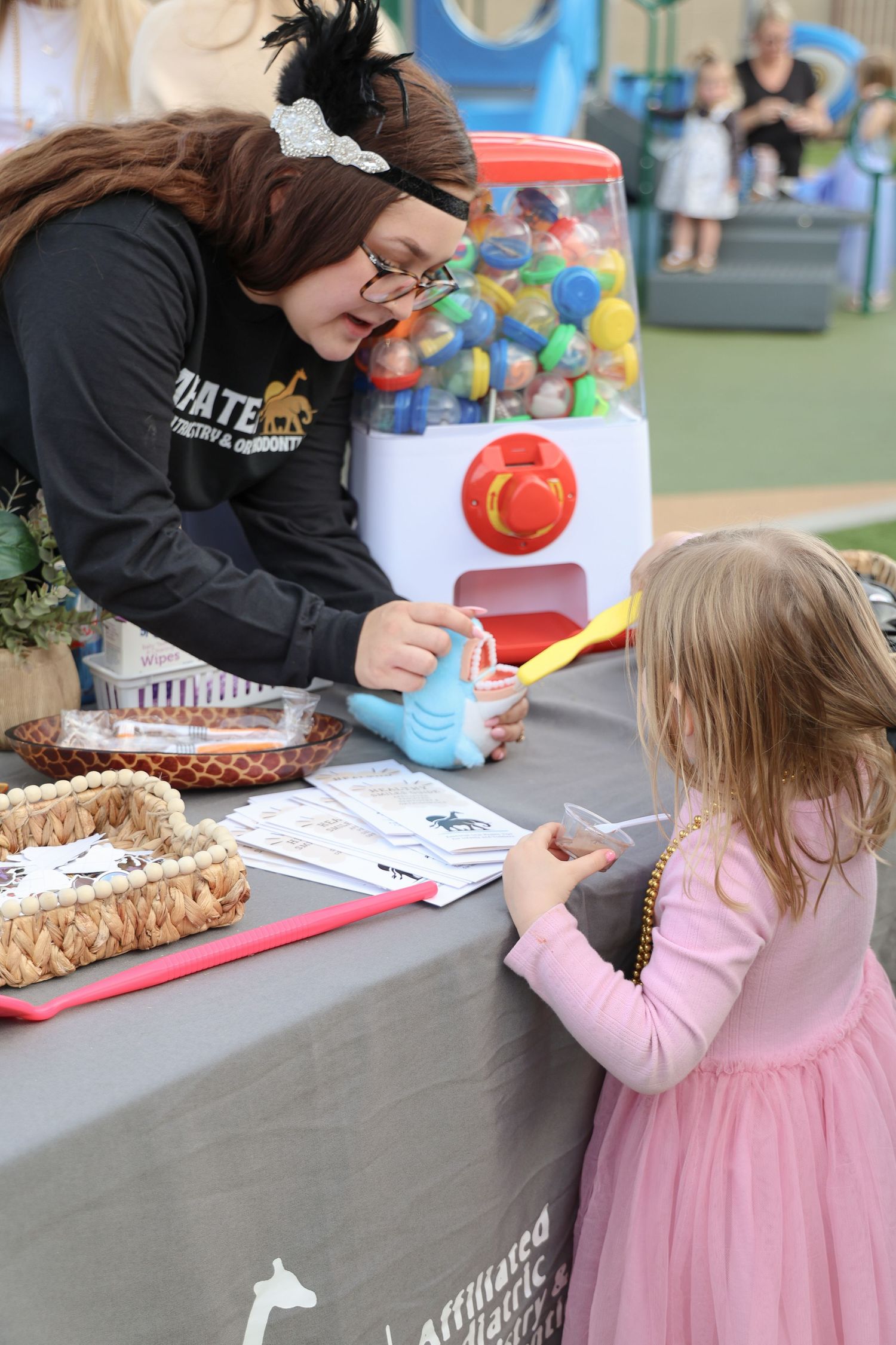 A child in a pink dress participates in an activity at a table with colorful materials and books.