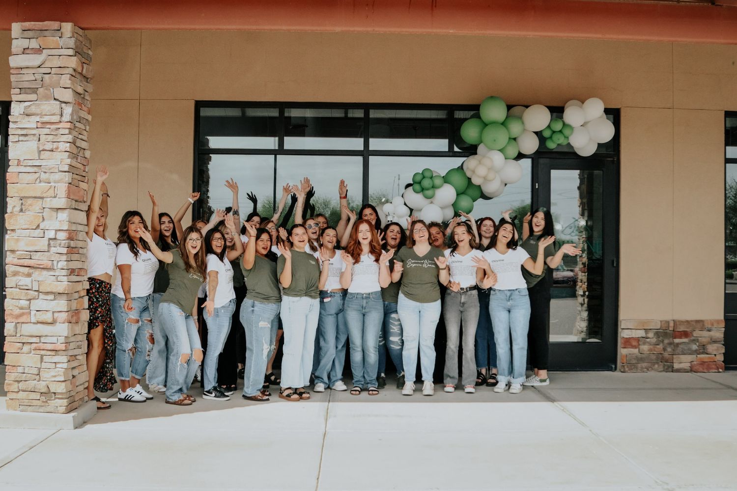 Group photo of people in matching outfits standing together outside a commercial building.