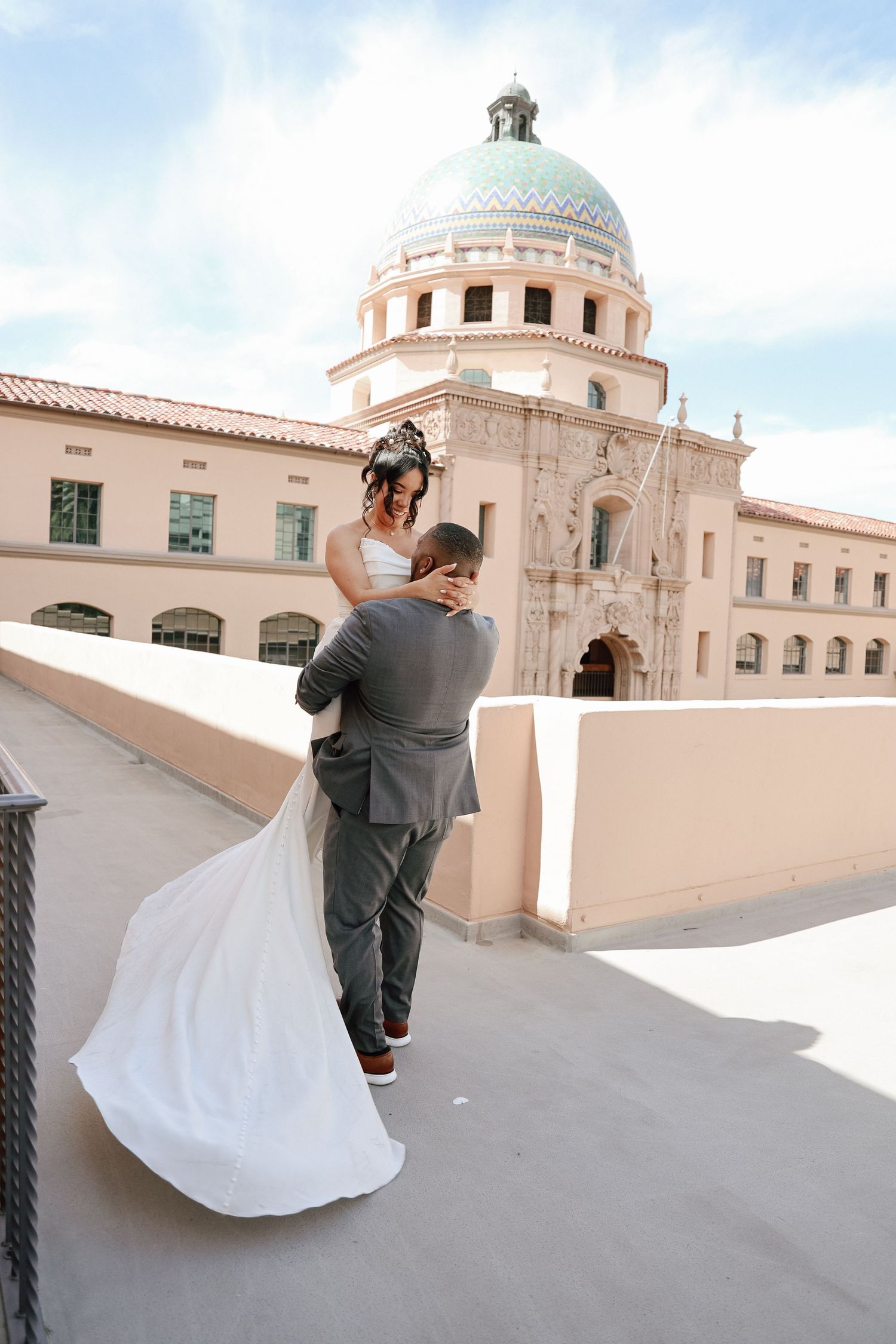 A romantic lift and embrace on a balcony with a stunning domed building in the background.