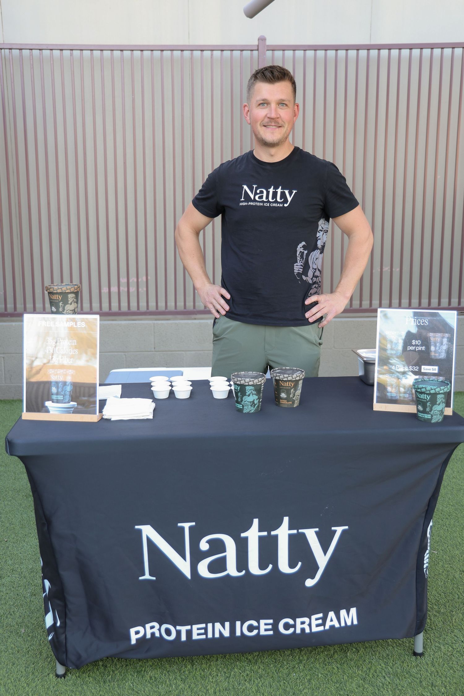 Natty protein ice cream display booth with black tablecloths and product samples set up at an outdoor event.