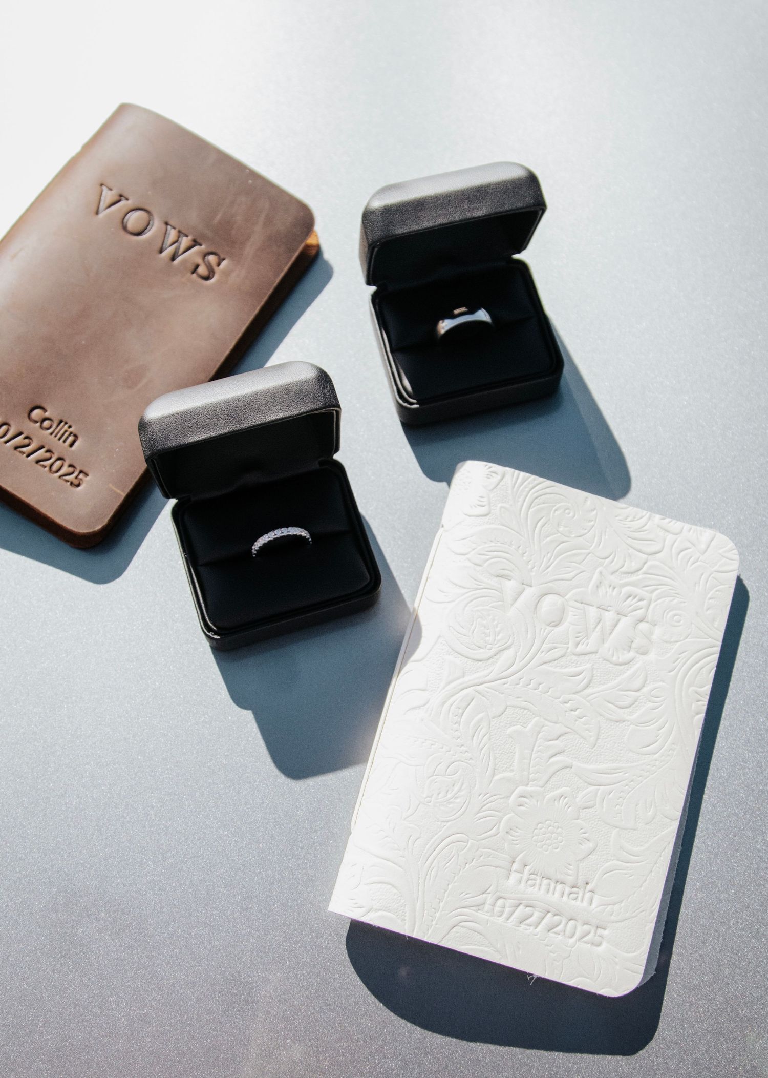 Elegant ring boxes in black, white, and tan leather displayed on a light gray background.
