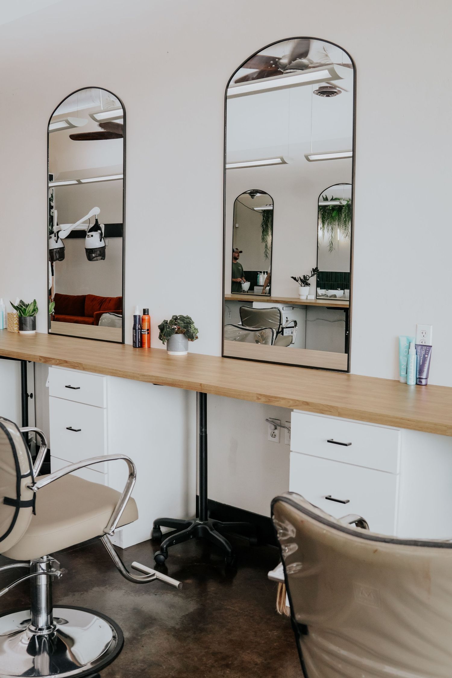 Modern salon workspace with minimalist styling stations featuring mirrors and wooden counters.