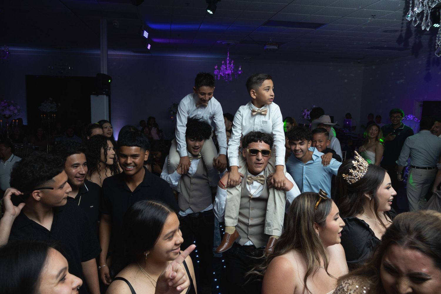 A lively crowd of people enjoying themselves at a dimly lit nightclub with purple lighting in the background.