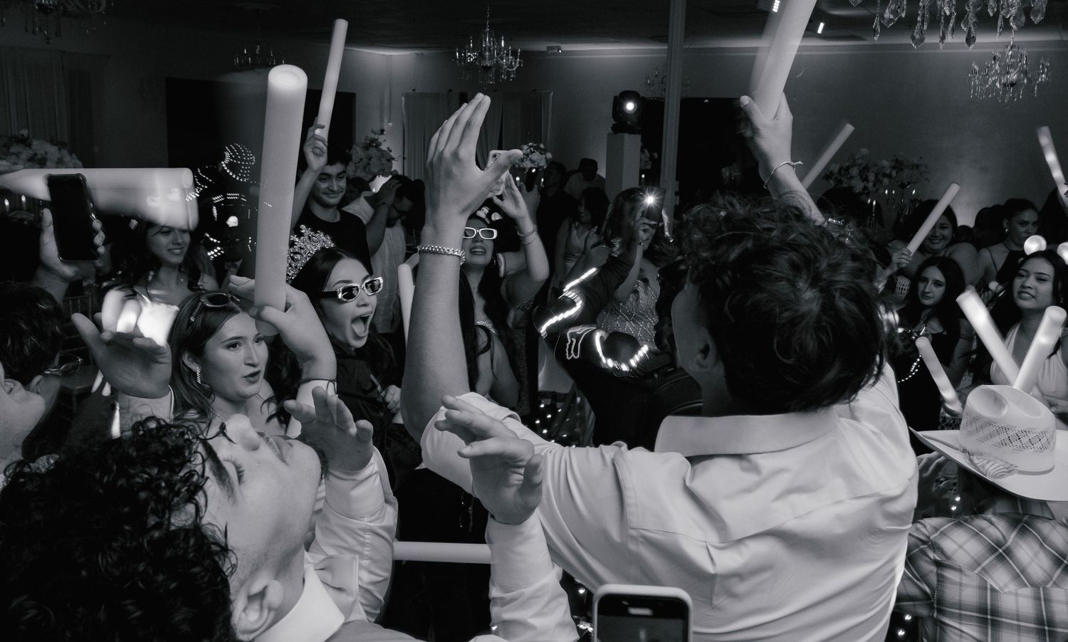 A black and white panoramic photo shows an energetic crowd with raised arms at what appears to be a concert or event.