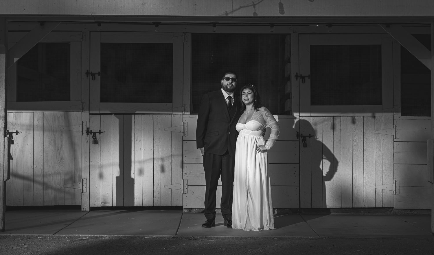 Black and white wedding photo with couple posing against wooden doors. At Rancho Carrillo