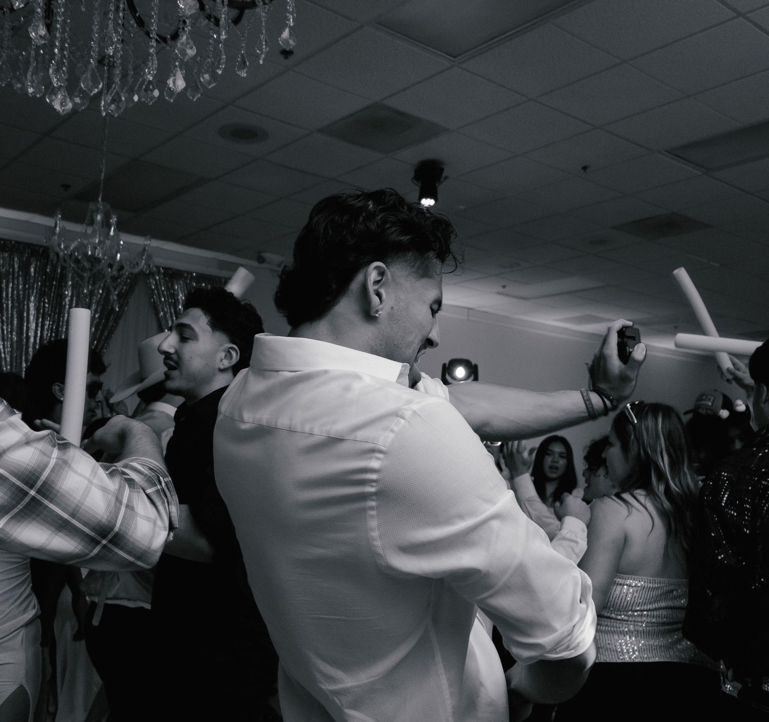 People dancing together in a dimly lit room during what appears to be a celebration or party event.