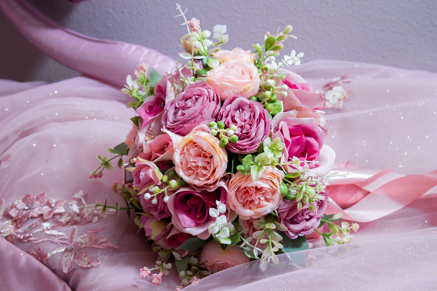 Romantic pink floral arrangement with roses and delicate greenery on soft fabric. At a Quinceañera