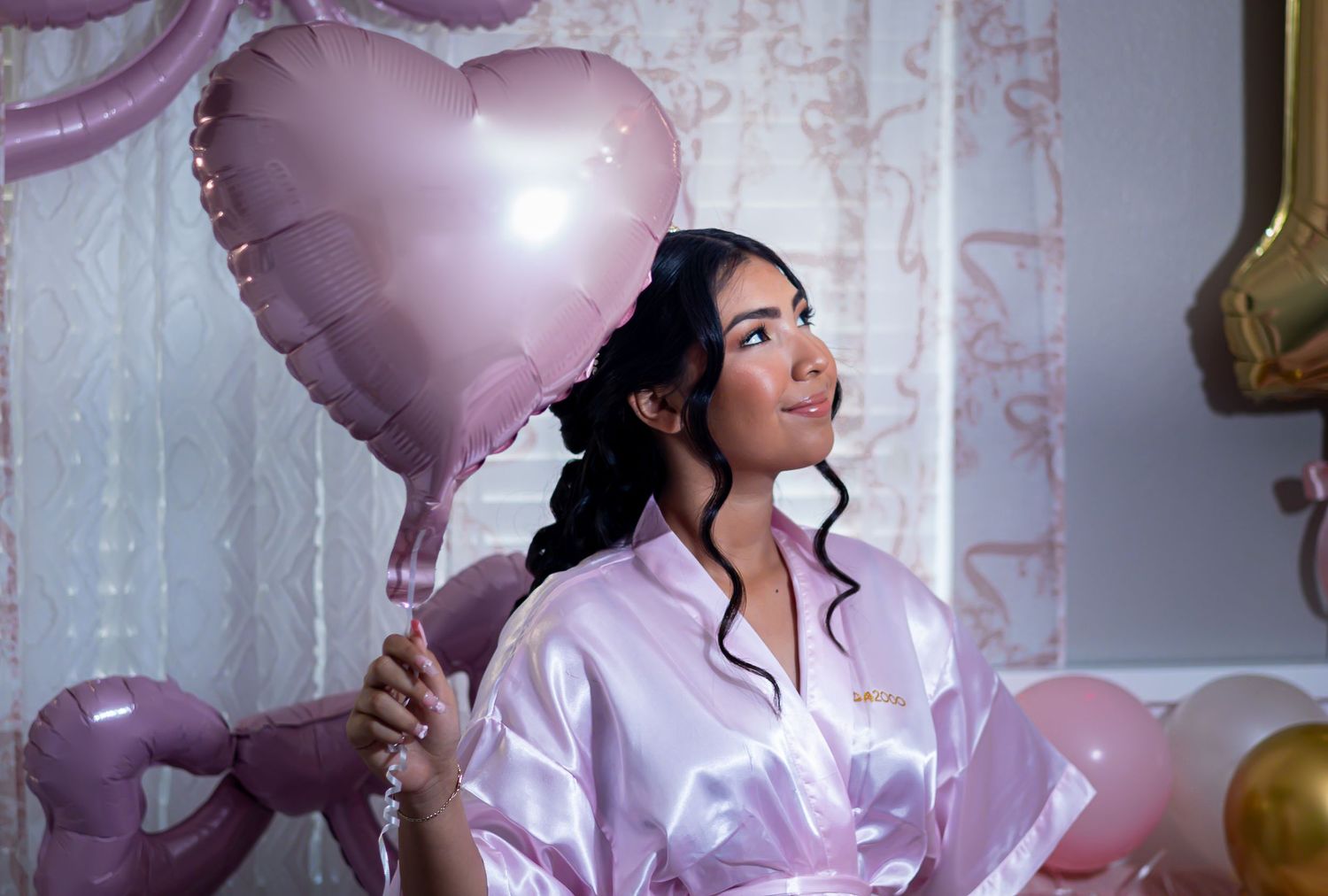 Candid celebration shots with pink heart balloons and satin loungewear. At a Quinceañera
