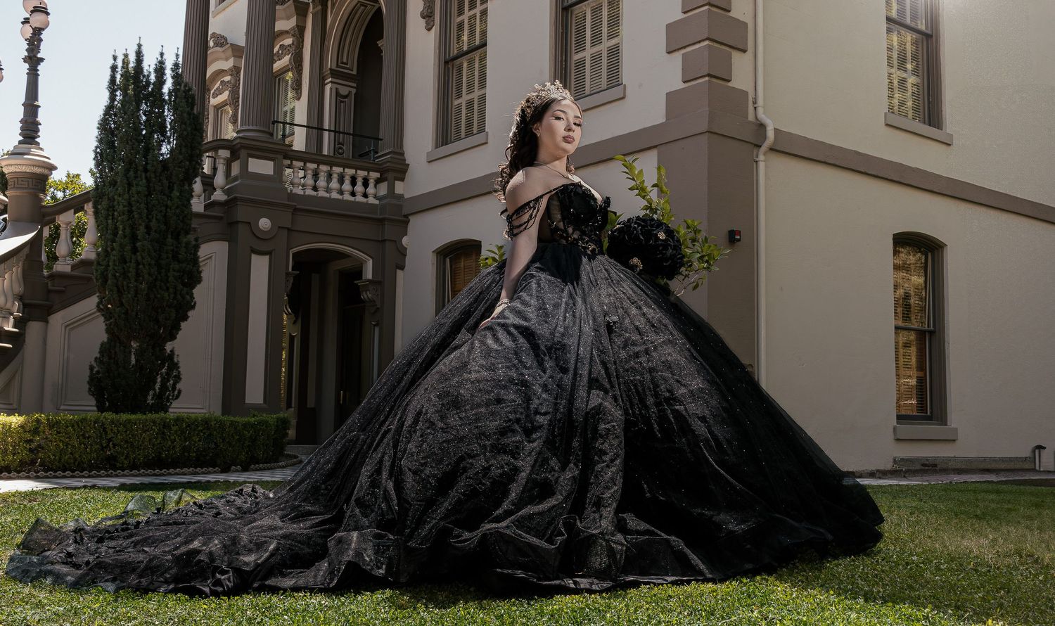 A series of outdoor photographs showing a dark sculptural figure in flowing fabric against white building walls and grass.