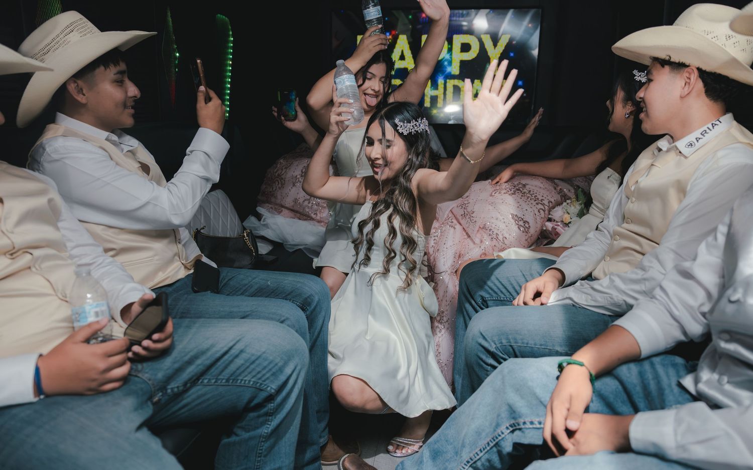 Group of teens in cowboy hats celebrating New Year's Eve party, dancing and having fun in a dimly lit venue.