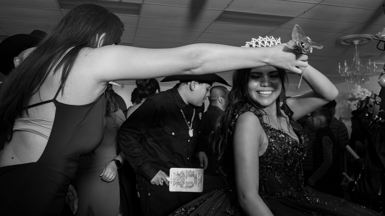 People dancing and celebrating at a party with arms raised in black and white photography.