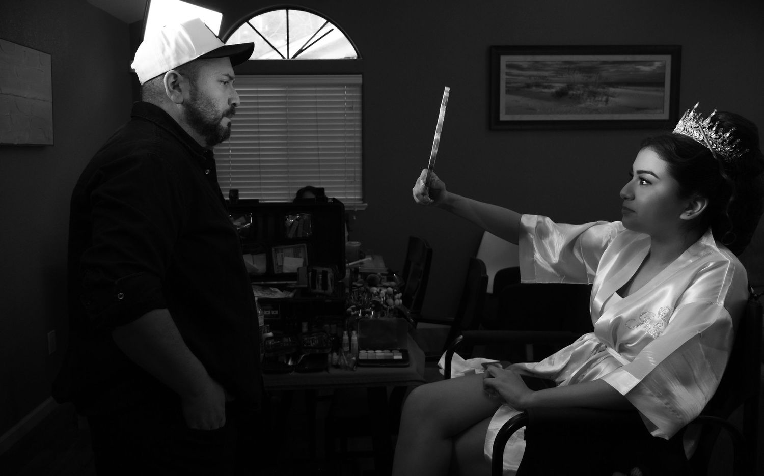 Behind-the-scenes preparation shot in dim lighting showing makeup application process. At a Quinceañera
