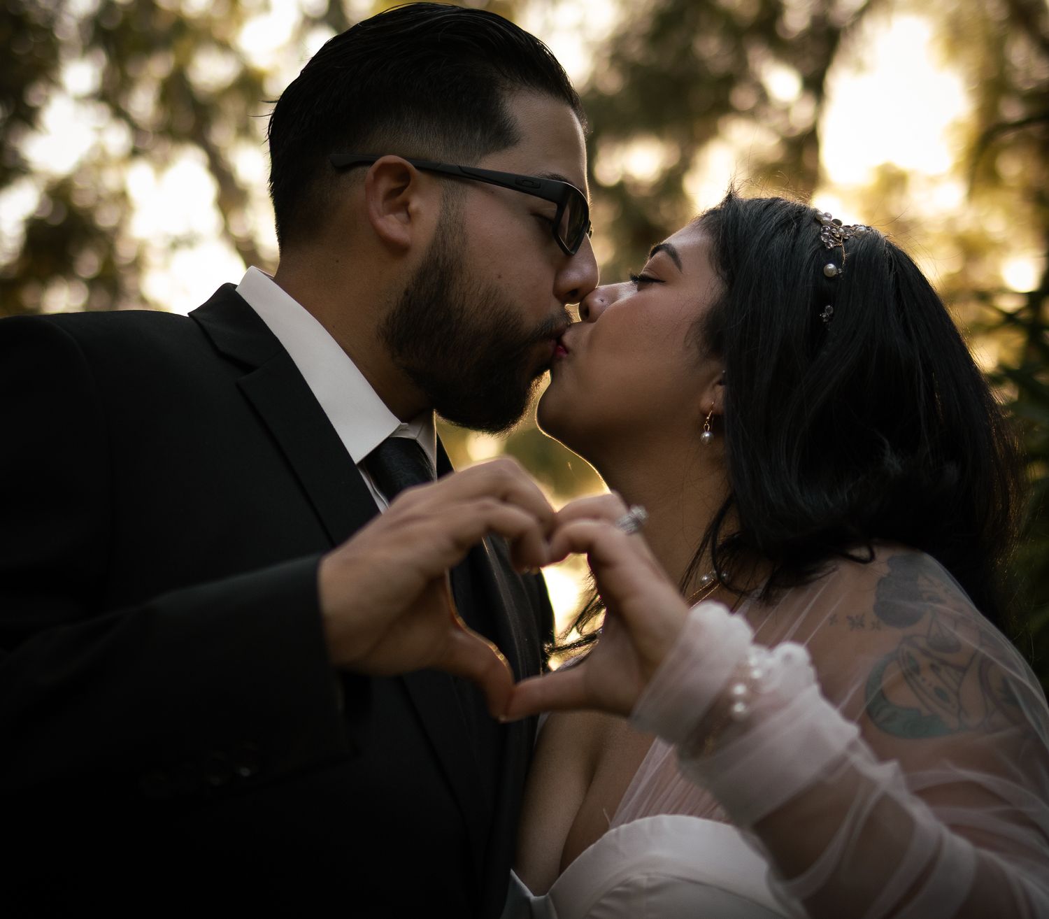 A romantic silhouette of a couple sharing a tender kiss at sunset with a dreamy golden bokeh background.