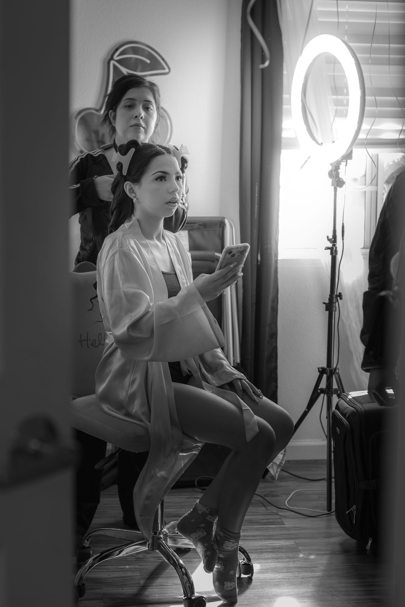 Behind-the-scenes black and white photo showing preparation with lighting equipment and camera setup. At a Quinceañera