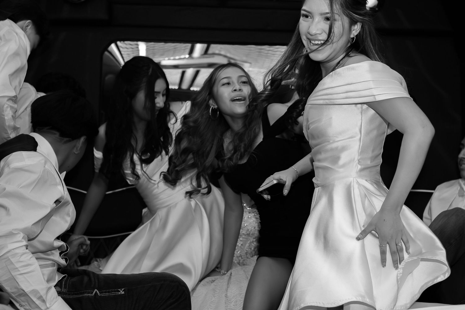 Three women in white dresses laughing and having fun at a celebration.