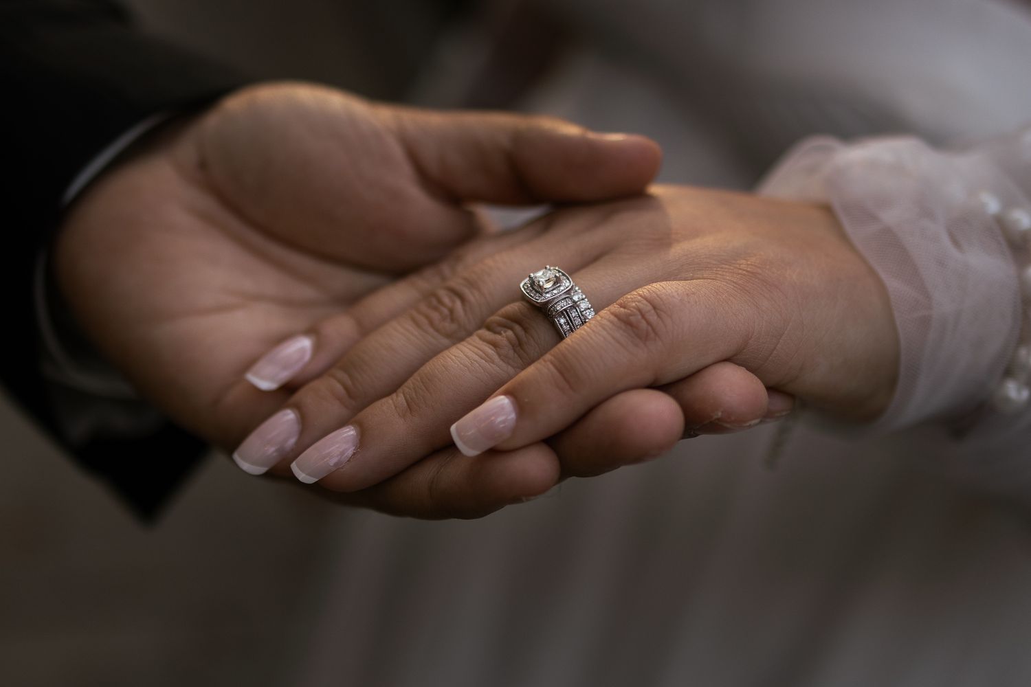 Close-up of hands holding a wedding ring during a romantic ceremony. At Rancho Carrillo
