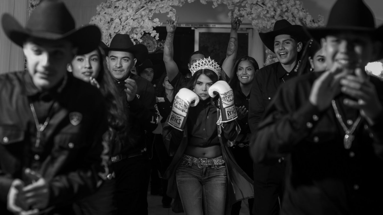 A black and white photograph shows a crowd of spectators at a sporting event cheering and celebrating.