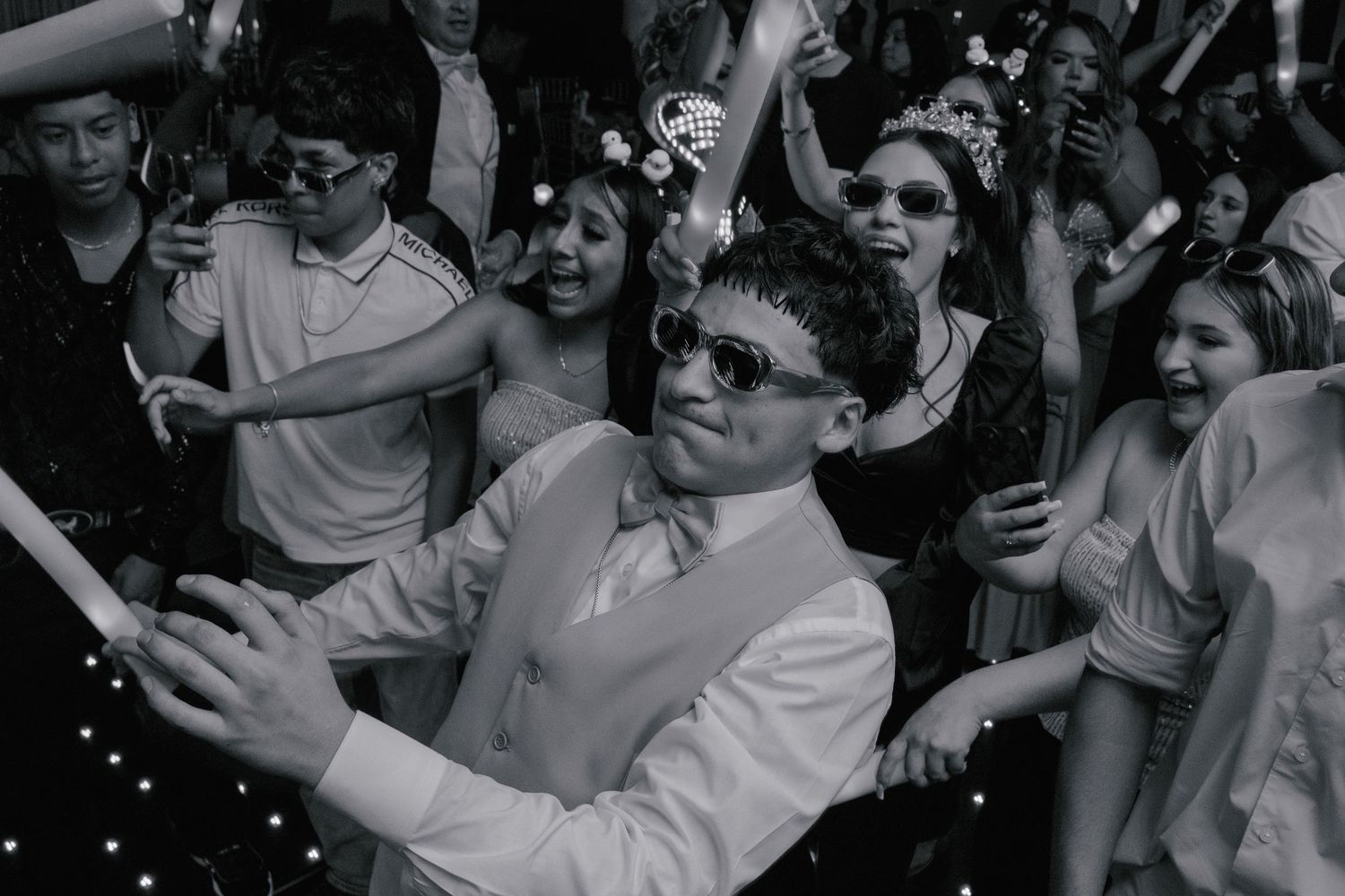 Energetic crowd dancing with raised arms at a lively indoor celebration. At a Quinceañera