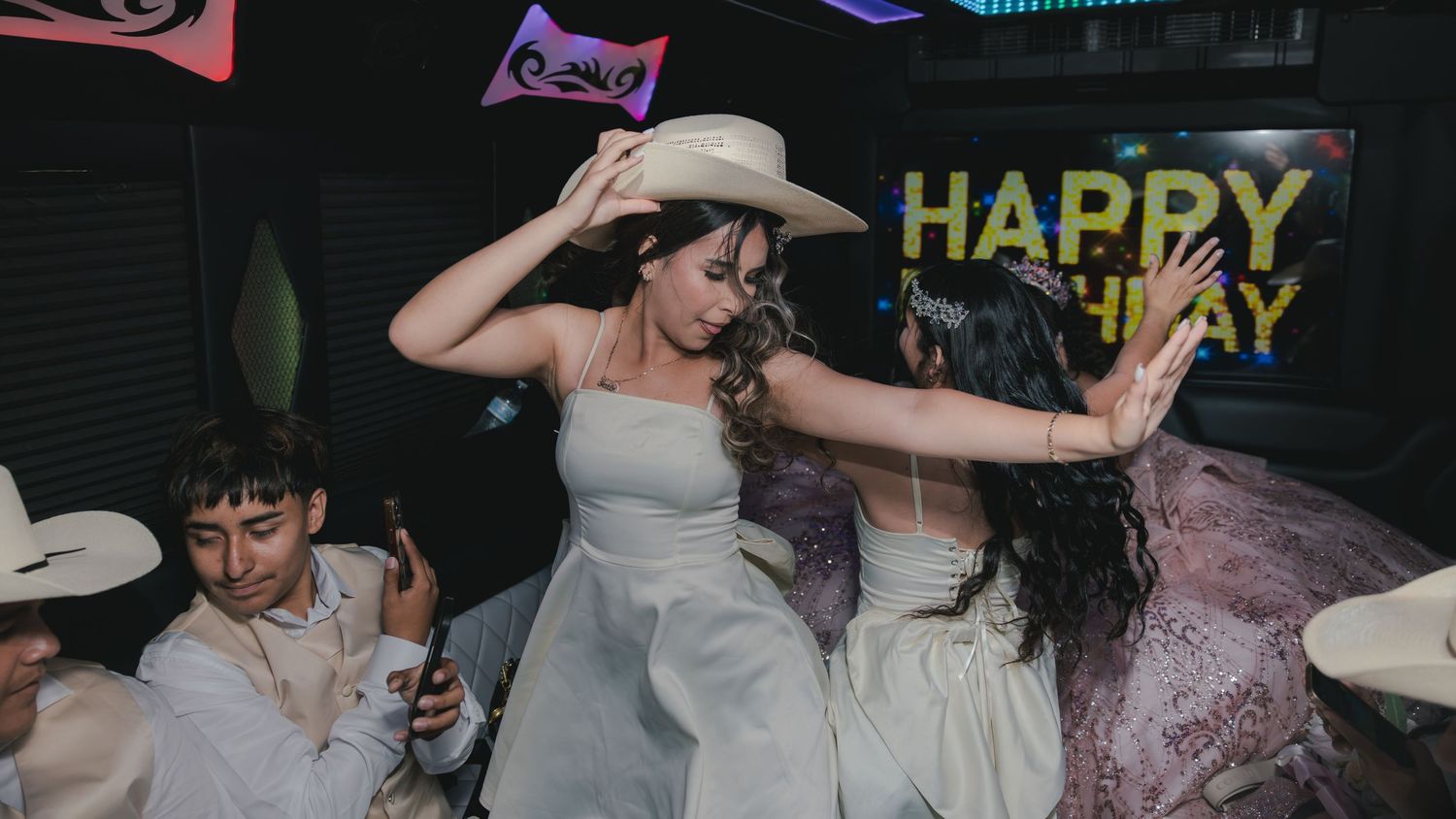 Women in white dresses dancing at a birthday party celebration inside a decorated venue with Happy Birthday sign.
