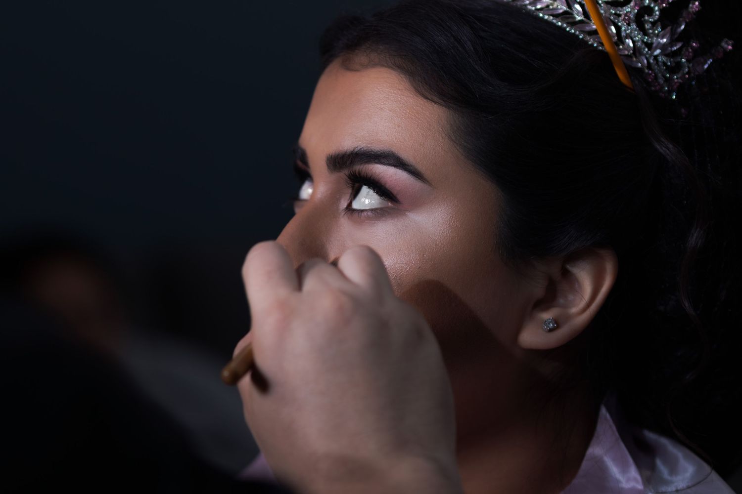 Close-up makeup application showing eyeshadow being applied with professional brush. At a Quinceañera
