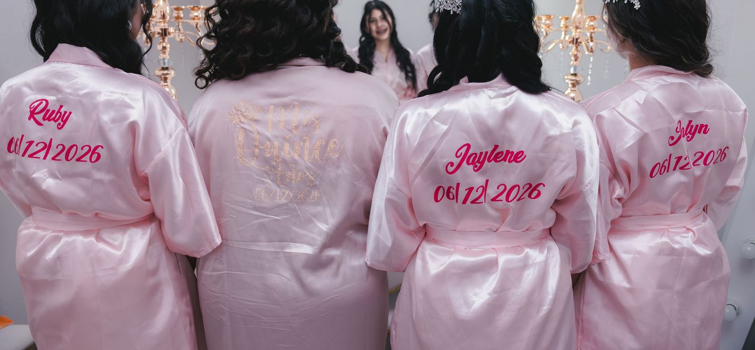 Pink satin personalized bridesmaid robes with names and date 04.12.2026 embroidered in red.