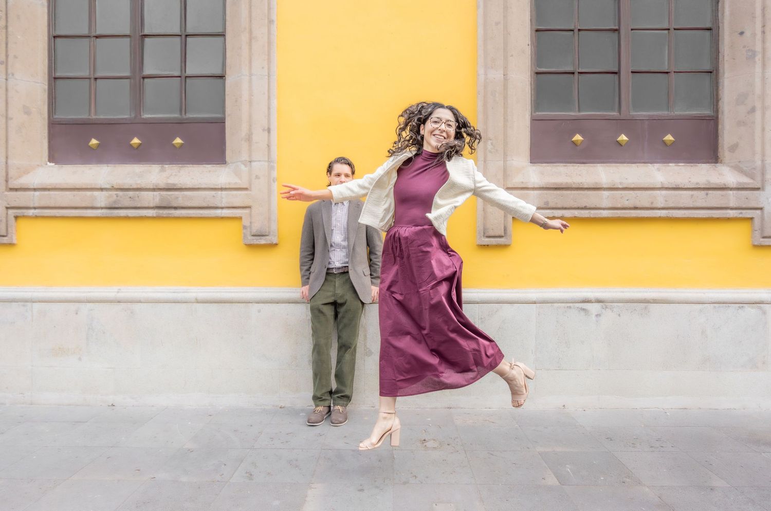 A series of five similar photos showing someone in a flowing burgundy dress posing against a yellow building exterior.